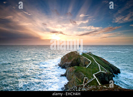 Crepuscular Rays Over South Stack Lighthouse at Sunset, Anglesey, North Wales, UK Stock Photo