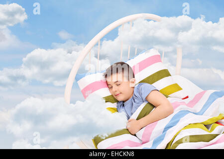 Cute little boy sleeping on a bed in the clouds Stock Photo