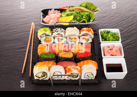 Delicious sushi rolls served on black plate and stone Stock Photo