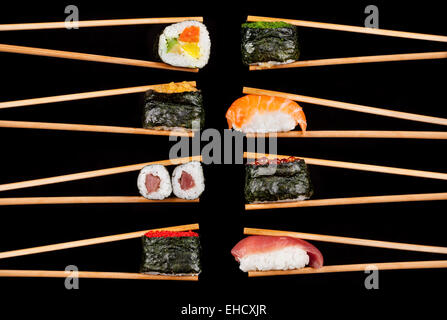 Set of sushi pieces in chopsticks, isolated on black background Stock Photo