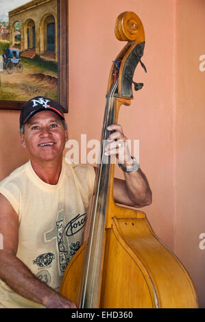 Vertical portrait of a man playing the double bass and singing on a street corner in Cuba. Stock Photo