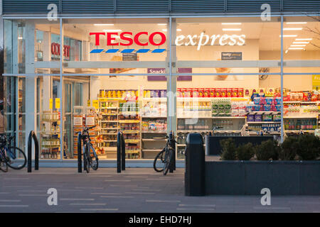 Tesco Express store, shop front exterior entrance, at dusk at Greenwich Peninsula, London, UK in March Stock Photo