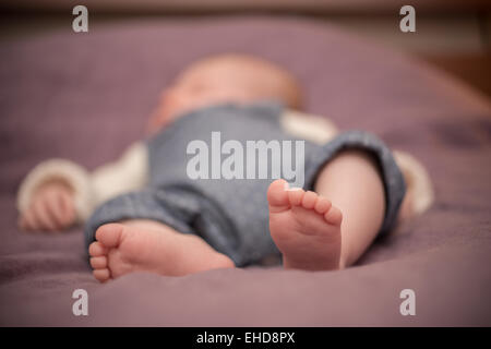 Baby sleeping barefoot on a bed Stock Photo