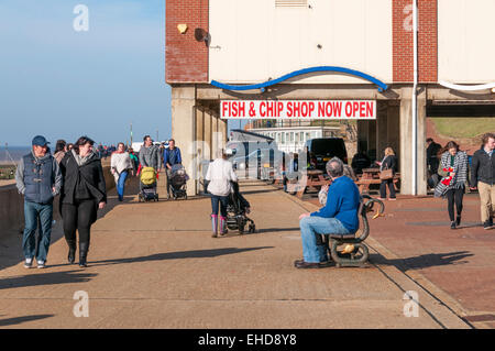 A Fish & Chip Shop Now Open sign on Hunstanton promenade beneath all that now remains of the pier. Stock Photo