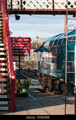 Guard leaning out of his train to collect a single line token as his train leaves Ramsbottom station on the East Lancs Railway Stock Photo