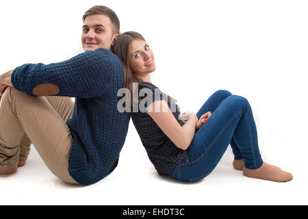 Happy young couple sitting back to back isolated Stock Photo