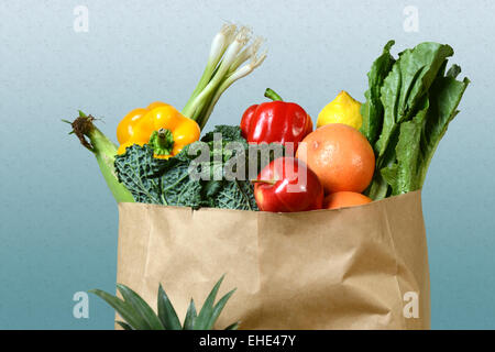 Assortment of fresh produce in grocery paper bag over gradient background Stock Photo