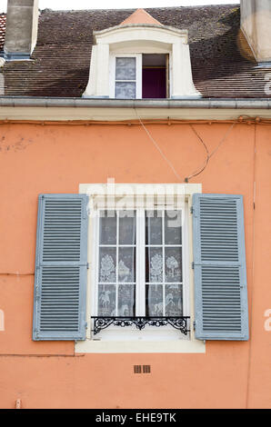 Lace curtains screen the window of a brightly painted house on the Rue d'Uxelles in Chalon-sur-Saône, Burgundy, France. Stock Photo