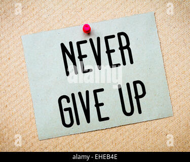 Recycled paper note pinned on cork board. Never Give Up Message. Concept Image Stock Photo