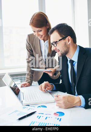 Two office workers watching something on laptop Stock Photo