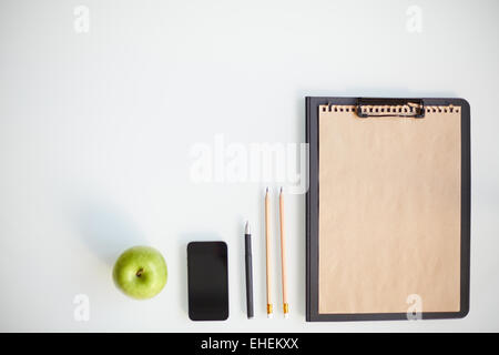 Writing instruments, smartphone, clipboard and apple Stock Photo