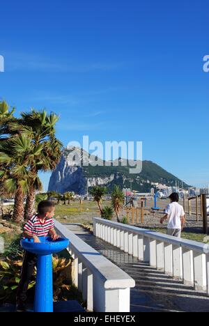 Boy taking a drink from a drinking fountain on La Linea beach in Spain with the Rock of Gibraltar to the rear, La Linea, Spain. Stock Photo