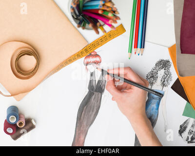 female hand drawing fashion sketch on desk with designing equipment Stock Photo