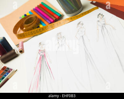 closeup of fashion designer workspace with sketches of evening gowns and designing equipment
