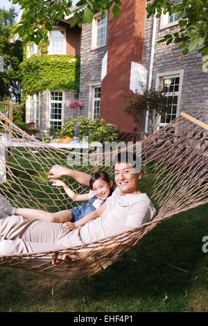 Father and daughter lying in a hammock in the garden Stock Photo
