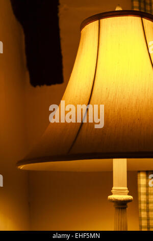 Bedroom floor lamp glowing orange in a corner of a room Stock Photo