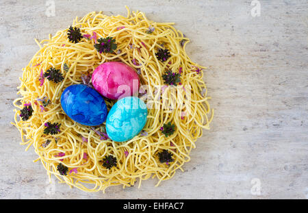 concept and idea Easter eggs in a nest of egg noodles on a light colored wood table. copy space room for text Stock Photo