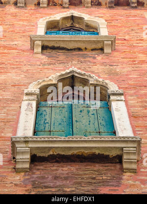 Old, medieval arched windows with blue and green shutters in Venice, Italy, perspective, low angle view. Stock Photo
