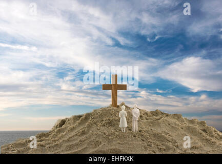 toy couple looking at the wooden holy cross on sand mountain Stock Photo