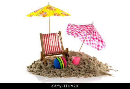 yellow and pink parasol in the sand with ball and bucket on the beach Stock Photo