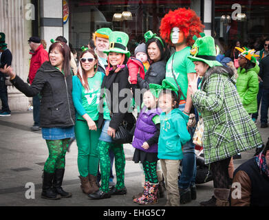 Family of Asian tourists enjoy St Patrick's day festival in Dublin Ireland wearing green clothes, facepaint and leprechaun hats. Stock Photo