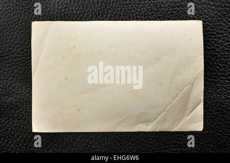 Old crumpled paper lying on black leather, as a frame, texture Stock Photo