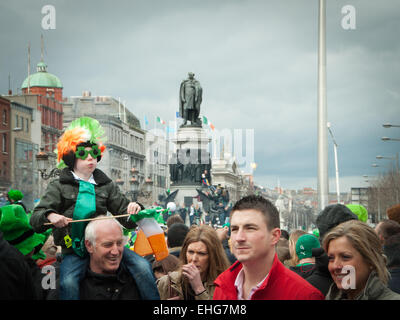 Young boy on father's shoulders has Irish wig, glasses and Irish flag on St Patrick's day in O'Connell Street Dublin Ireland Stock Photo