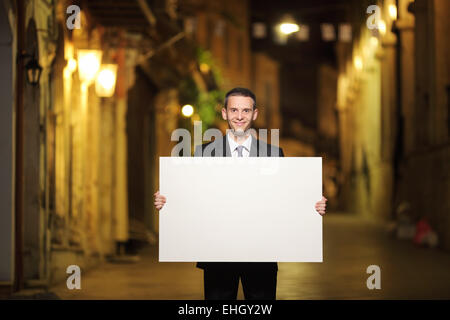 Businessman holding a blank panel in a city street Stock Photo