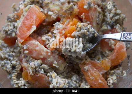 Close up of a healthy and hardy breakfast of oatmeal, blood oranges, and black chia seeds in a glass bowl with a silver spoon Stock Photo