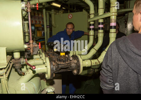 Ship's engineer Roman Horsel of German research vessel RV Sonne (old) shows scientists the engine room. Stock Photo