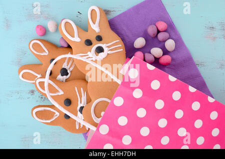 Easter bunny gingerbread cookies in pink polka dot gift bag on blue wood table. Stock Photo