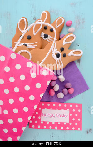 Easter bunny gingerbread cookies in pink polka dot gift bag on blue wood table. Stock Photo