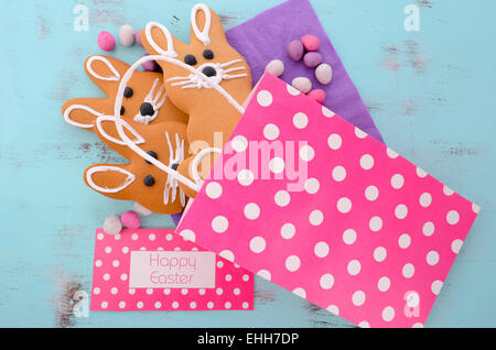 Easter bunny gingerbread cookies in pink polka dot gift bag on blue wood table. Stock Photo