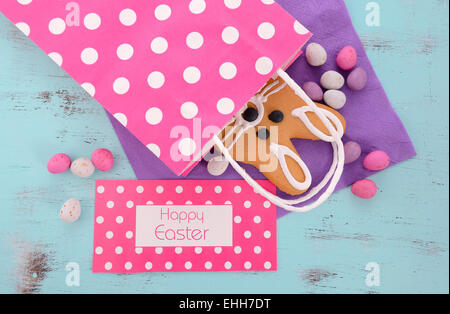 Easter bunny gingerbread cookies in pink polka dot gift bag on blue wood table. Stock Photo