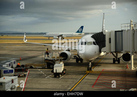 AUCKLAND, NEW ZEALAND, JANUARY 23, 2015: An Air New Zealand jet lands at Auckland Airport while another takes on passengers Stock Photo