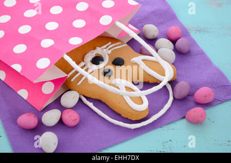 Easter bunny gingerbread cookies in pink polka dot gift bag on blue wood table. Stock Photo