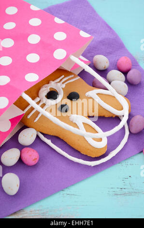 Easter bunny gingerbread cookies in pink polka dot gift bag on blue wood table. Stock Photo