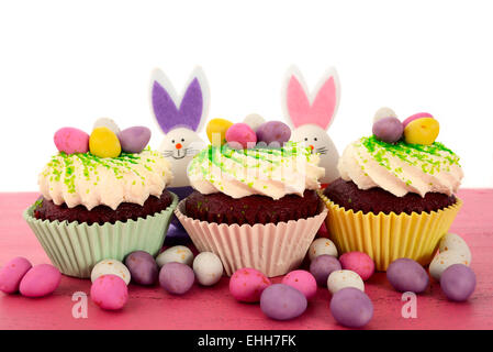 Happy Easter cupcakes with bunny easter eggs on pink wood table. Stock Photo