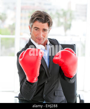 Self-assured businessman wearing boxing gloves Stock Photo