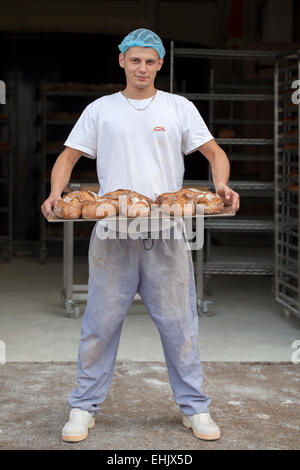 Baker holding a tray of freshly baked bread Stock Photo