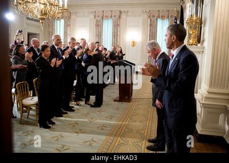 US Defense Secretary Chuck Hagel bows his head to the applause of President Barack Obama and attendees following the announcement of Hagel's resignation in the State Dining Room of the White House November 24, 2014 in Washington, DC. Stock Photo