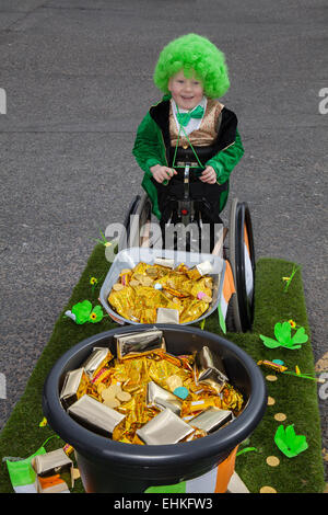 St. Patrick's Day Wheelchair user at Manchester, UK 15th March, 2015.  Wheelchair bound Daiton Berry Mellor 6 years old, a Spina bifida sufferer at the weekend Irish Festival. His dad has made a float as a Wheelbarrow full of gold coins and treasure.  The colourful procession set off from the Irish World Heritage Centre in Cheetham Hill before making its way to Albert Square.  Flag bearers representing the 32 counties in the Emerald Isle led the parade into the city centre, followed by floats from the city’s Irish associations. Stock Photo