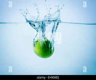 High speed freeze action shot of a lime splashing in water on white background Stock Photo