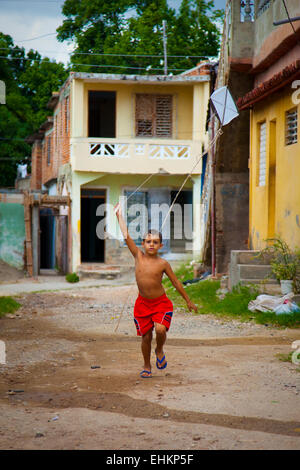 A boy flies a homemade kite in the street in Trinidad, Cuba Stock Photo