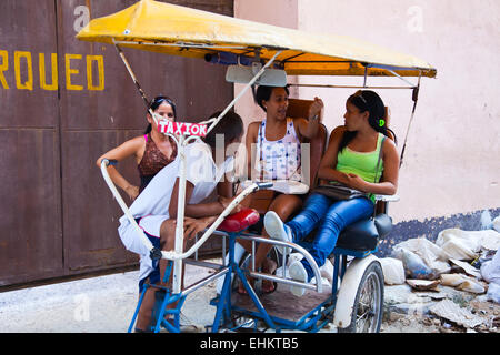 Young Cubans lounge on a bicycle taxi, Havana, Cuba Stock Photo