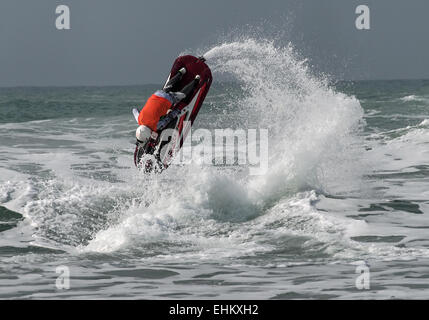 Male jet ski competitor performs aerial action moves in large breaking surf on Newquay Fistral beach Stock Photo