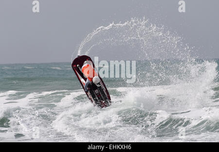 Male jet ski competitor performs aerial action moves in large breaking surf on Newquay Fistral beach Stock Photo