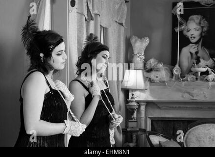 Young lady wearing vintage clothing in deep thought with reflection in mirror and a picture of Marilyn Monroe  black and white Stock Photo