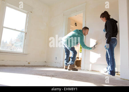 Mixed race couple painting walls of new home Stock Photo