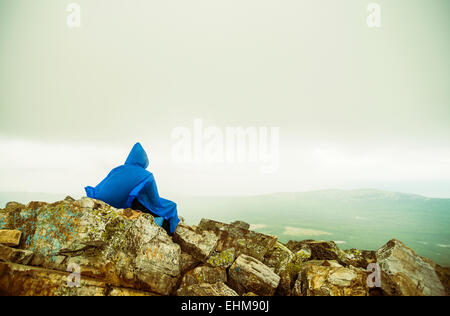 Caucasian hiker sitting on rocky hilltop Stock Photo